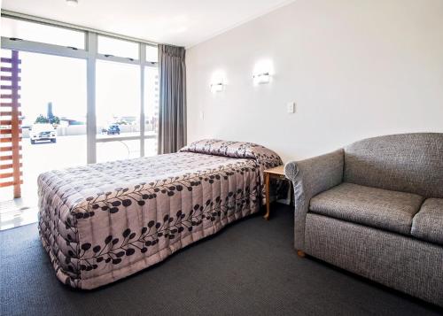 a bedroom with a bed and a couch and a chair at Aspree Motor Inn in Palmerston North