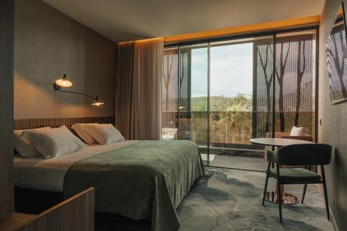 a hotel room with a bed and a window and a table at Hotel Leiriartem by Grupo Quinta dos Lagos in Leiria