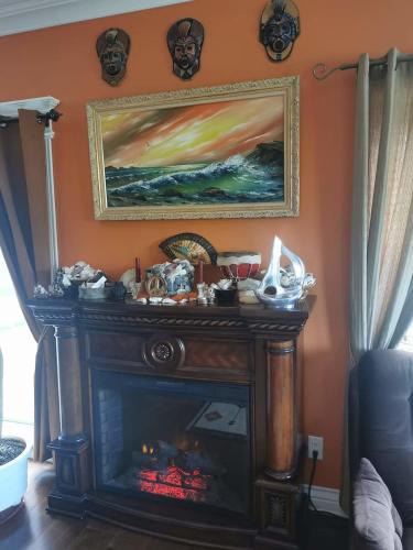 a fireplace in a living room with a painting on the wall at Gîte Le Trésor Caché Bed & Breakfast in Chelsea