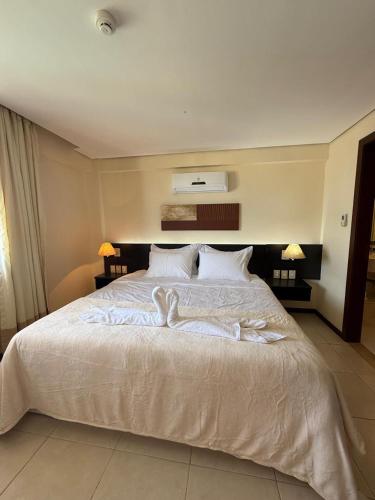 a bedroom with a large bed with white sheets at Kariri Beach Residence in Caucaia