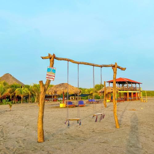 a swing set on a beach with a resort at Surfing Turtle Lodge in Poneloya