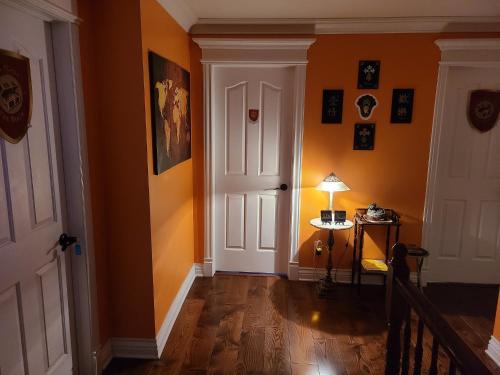 a hallway with orange walls and a white door at Gîte Le Trésor Caché Bed & Breakfast in Chelsea