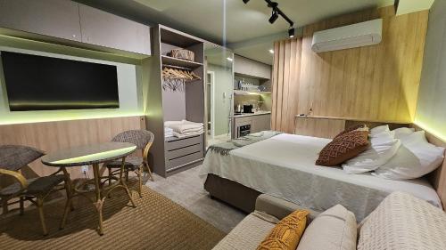 a hotel room with a bed and a table and a tv at Estúdio Moderno em área nobre de Porto Alegre - Conforto e Aconchego em Cada Detalhe in Auxiliadora