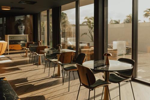a restaurant with tables and chairs and large windows at Hotel Leiriartem by Grupo Quinta dos Lagos in Leiria