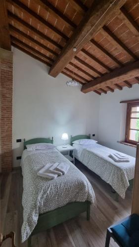 two beds in a room with wooden ceilings at Casa Ottavina in Borgo a Buggiano
