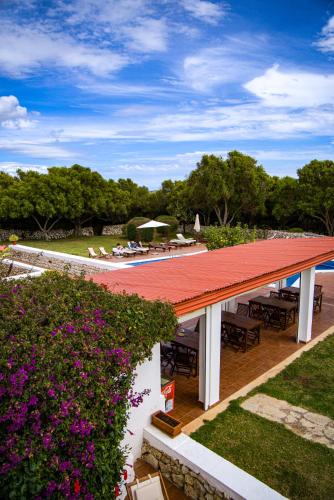 a patio with a red roof and tables and flowers at Agroturismo Binissafullet Vell in Sant Lluis