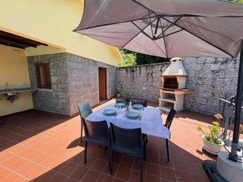 ein Tisch mit Stühlen und einem Sonnenschirm auf einer Terrasse in der Unterkunft Casa do Recanto by Sé Apartamentos in Vieira do Minho