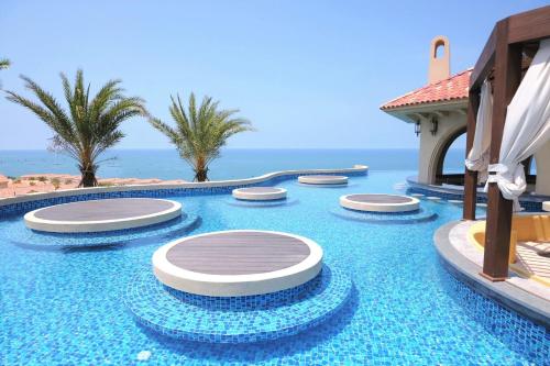 a pool at a resort with the ocean in the background at Centara Mirage Resort Mui Ne in Mui Ne