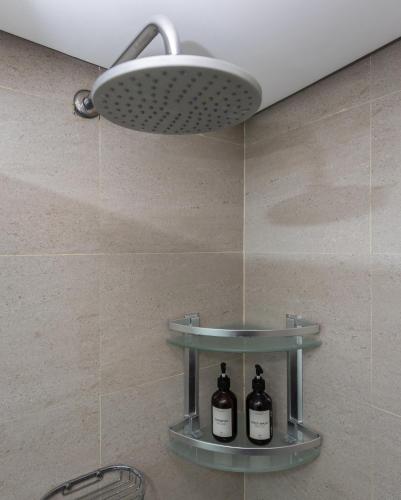 a shower with a sink and two bottles on a shelf at R2N Cosy Haven - BE Residences Lahug near IT Park Cebu in Cebu City