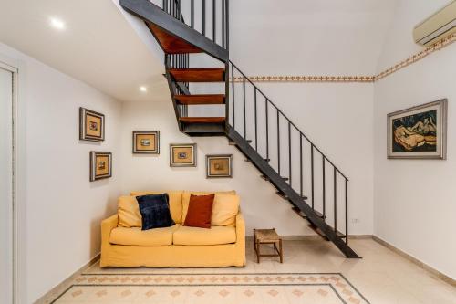 een woonkamer met een gele bank en een trap bij U Quardianu - Le Case di Valentina in Gallipoli