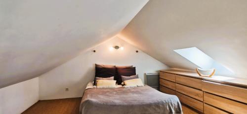 - une chambre mansardée avec un lit et une commode dans l'établissement Maison Bérenger Normandie- 6 personnes, à Saint-Manvieu-Bocage