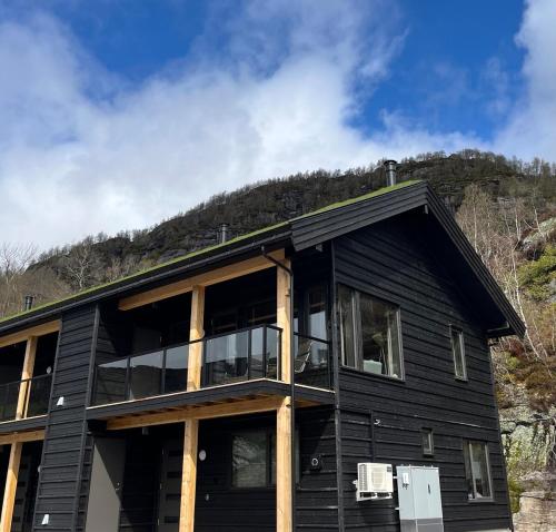 a black house with a mountain in the background at Family-Friendly Mountain Holiday Home with Lakeviews, Close to Beach in Tjørhom