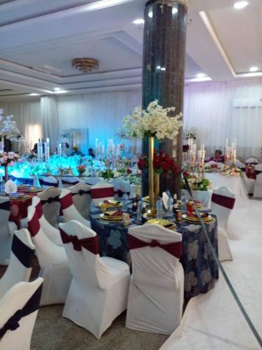 a banquet hall with white chairs and a table with flowers at Omni Grand Hotel and conference center jabi abuja in Abuja