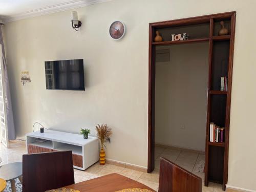 a living room with a table and a tv on the wall at Your Home Away From Home in Kampala