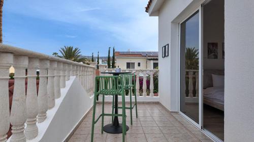a balcony with a green table and chairs on it at Villa Talya in Peyia