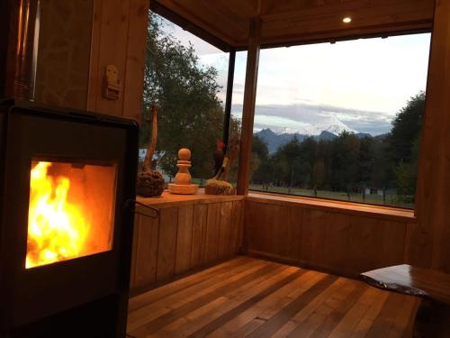 a fireplace in a room with a view of the mountains at Cabañas Los Canelos Pucon, Hermosa Granja de 20 hectaréas a orillas del Río Liucura in Pucón