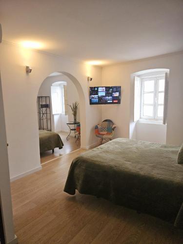 a bedroom with a bed and a tv on the wall at Alcamim Guesthouse in Elvas