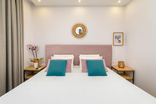 a bedroom with a large bed with blue and pink pillows at KORINA APART HOTEL KAVOS in Kavos