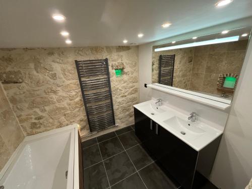 a bathroom with a sink and a mirror and a tub at La maison du village in Bajonnette