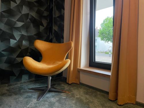 a orange chair sitting in front of a window at PAULINEN Residenz in Detmold