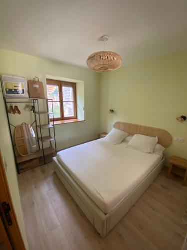 - une chambre avec un grand lit blanc et un lustre dans l'établissement La Grange de la Fiole, à Blanot