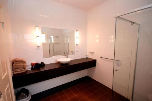 a bathroom with a sink and a shower with a mirror at Sundowner Motel Hotel in Whyalla
