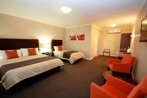 ein Hotelzimmer mit 2 Betten und einem Stuhl in der Unterkunft Sundowner Motel Hotel in Whyalla