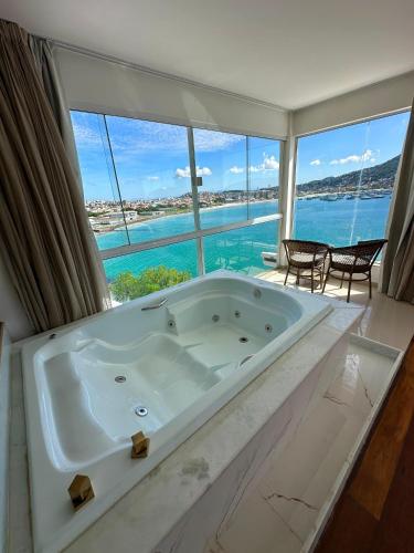 a bath tub in a bathroom with a view of the ocean at Pousada Atalaia Boutique FR in Arraial do Cabo