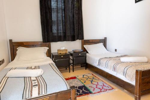 a bedroom with two beds and a table and a window at Hola Surf Morocco in Agadir