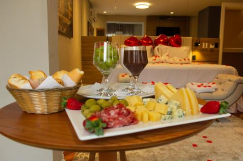 a table with two glasses of wine and a plate of food at Champet Boutique Hotel in Campos do Jordão