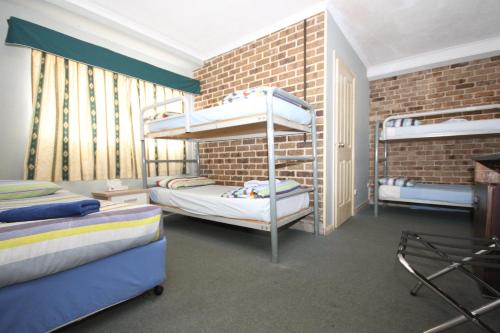 a bedroom with two bunk beds and a brick wall at Acacia Snowy Motel in Jindabyne