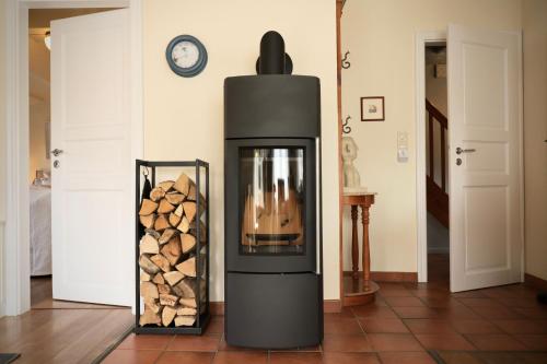 a black fireplace with a pile of fire wood at Haus Wattwurm in Midlum
