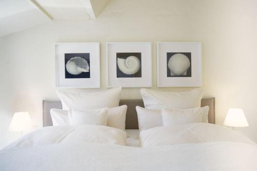 a bedroom with white pillows and pictures on the wall at Haus Wattwurm in Midlum