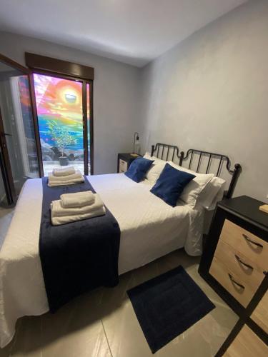 a bedroom with two beds with blue pillows and a window at A Casiña de Tivo in Fisterra