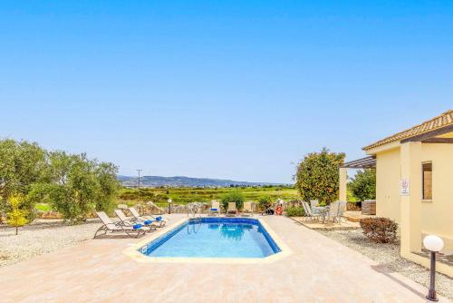 a swimming pool with chairs and a house at Villa Lime Tree in Lachi