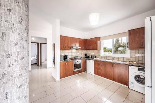 a kitchen with wooden cabinets and a washer and dryer at Villa Lime Tree in Lachi