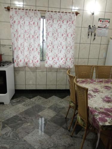 a kitchen with a table and chairs and curtains at Casa do Aconchego in Rio Forcação