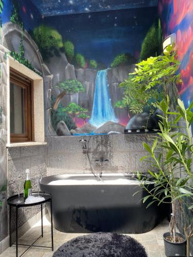 a bath tub in a bathroom with a waterfall mural at A Casiña de Tivo in Fisterra