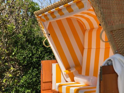an orange and white striped chair in a wicker chair at Haus Strandläufer in Midlum