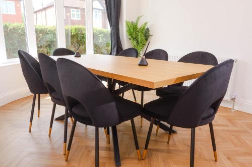 a dining room table with black chairs around it at Exquisite 3BD Nordic Retreat with Parking in Timperley
