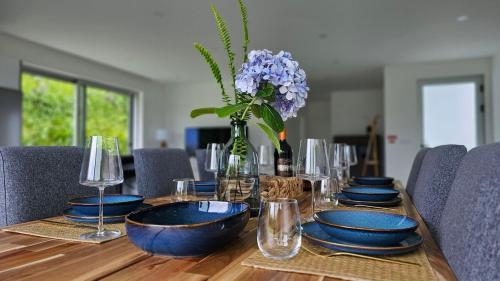 a wooden table with blue plates and a vase with flowers at GuestReady - Seaview Villa with Private Pool in Bretanha