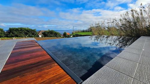 a swimming pool with a wooden floor and the water at GuestReady - Seaview Villa with Private Pool in Bretanha