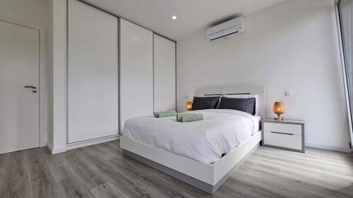 a white bedroom with a large bed and a night stand at GuestReady - Seaview Villa with Private Pool in Bretanha