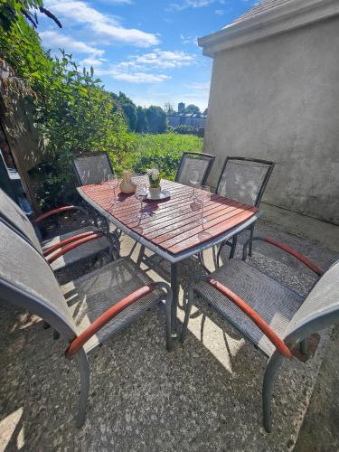 a wooden table with four chairs and a table with drinks on it at Wolfe Tone Apartment in Sligo