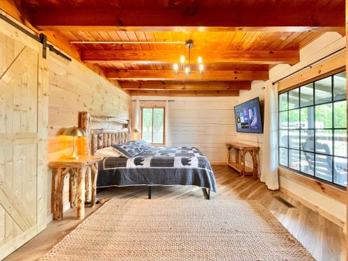 Dormitorio en cabaña de madera con cama y TV en Modern lake side nest• HOTUB Fenced YARD king beds, en Sevierville