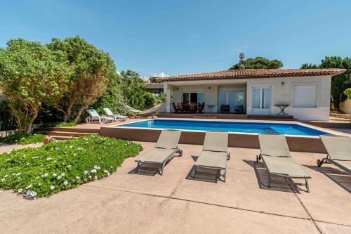 a group of lounge chairs and a swimming pool at Belle villa avec accès direct à la mer in Calvi