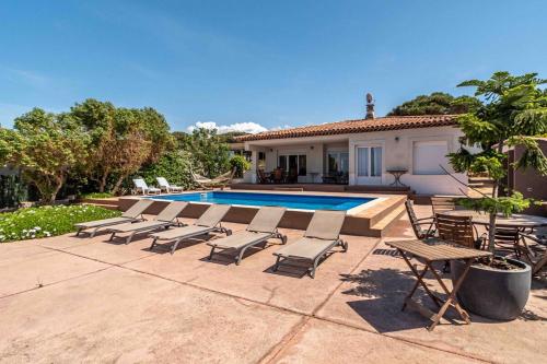 a group of lounge chairs next to a swimming pool at Belle villa avec accès direct à la mer in Calvi