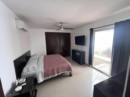 a bedroom with a bed and a large window at Puerto Aventuras Apartment wifi pools barbecue family in Puerto Aventuras