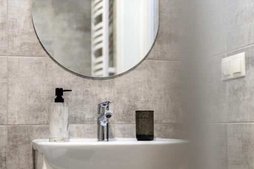 ein Badezimmer mit Waschbecken und Spiegel in der Unterkunft Taikos STUDIO Apartamentai-2 in Klaipėda