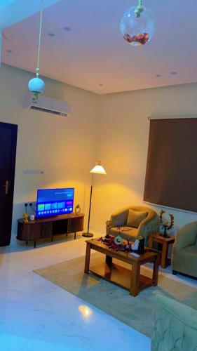 a living room with a tv and a couch and a table at شقة مخدومة VIp in Hafr Al Baten